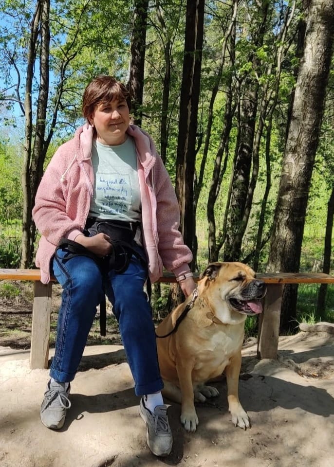 Наталья на скамейке в лесу, рядом сидит Рада, собака породы Ка де Бо